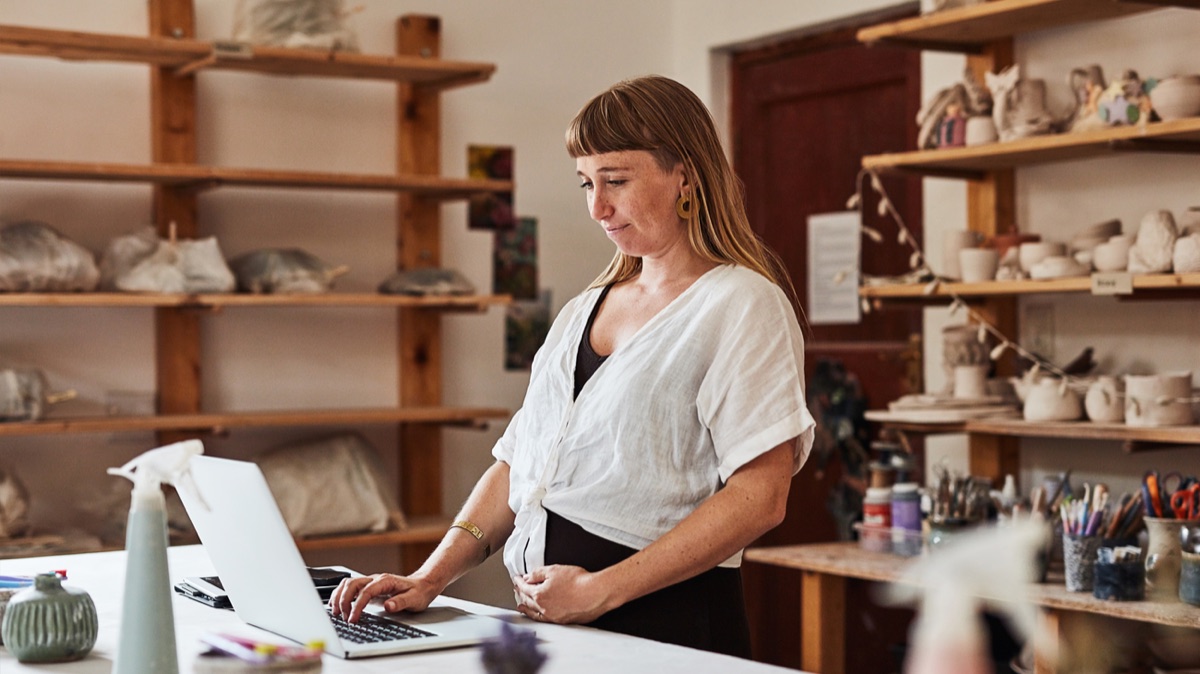 A merchant working on a laptop in a ceramics studio